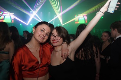 Des enfants colorient des dessins autour d'une table ronde, entourés d'adultes dans un espace intérieur animé.