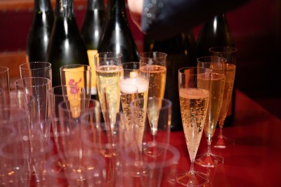 Des enfants colorient des dessins autour d'une table ronde, entourés d'adultes dans un espace intérieur animé.