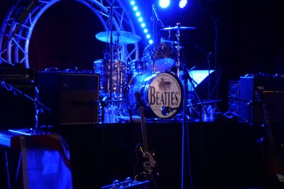 Des enfants colorient des dessins autour d'une table ronde, entourés d'adultes dans un espace intérieur animé.