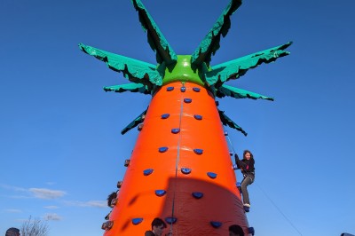 Des enfants colorient des dessins autour d'une table ronde, entourés d'adultes dans un espace intérieur animé.