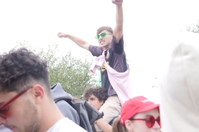 Des enfants colorient des dessins autour d'une table ronde, entourés d'adultes dans un espace intérieur animé.