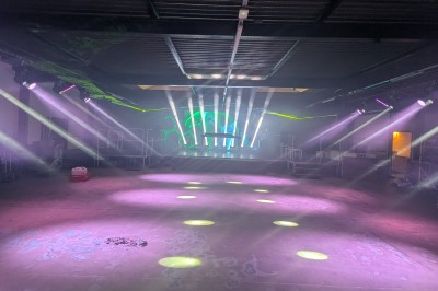 Des enfants colorient des dessins autour d'une table ronde, entourés d'adultes dans un espace intérieur animé.