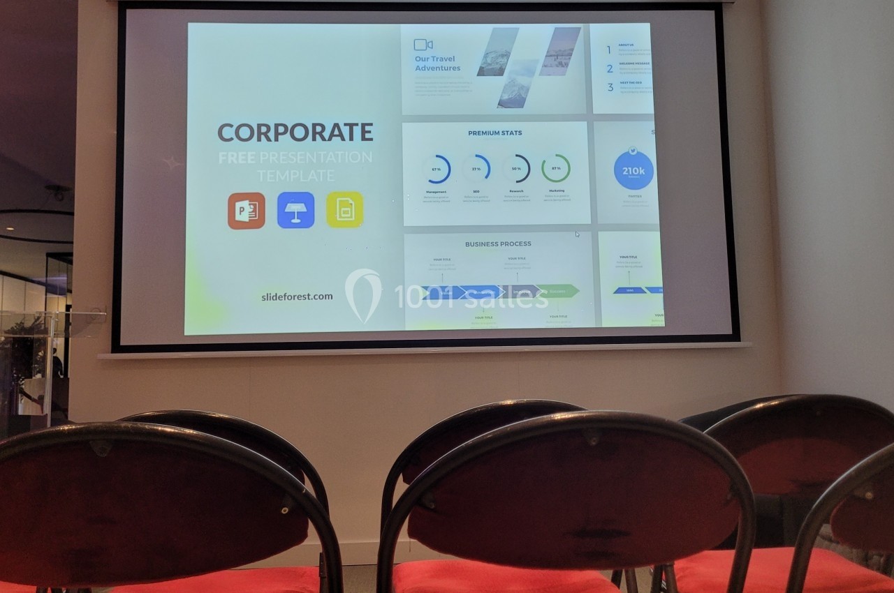 Écran de présentation affichant un modèle de diaporama d'entreprise dans une salle avec des chaises vides.