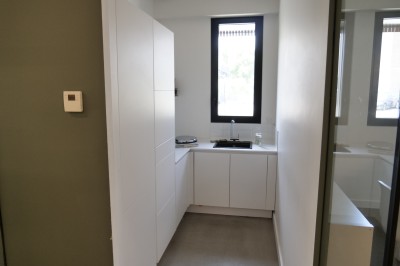 Des enfants colorient des dessins autour d'une table ronde, entourés d'adultes dans un espace intérieur animé.