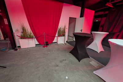 Des enfants colorient des dessins autour d'une table ronde, entourés d'adultes dans un espace intérieur animé.