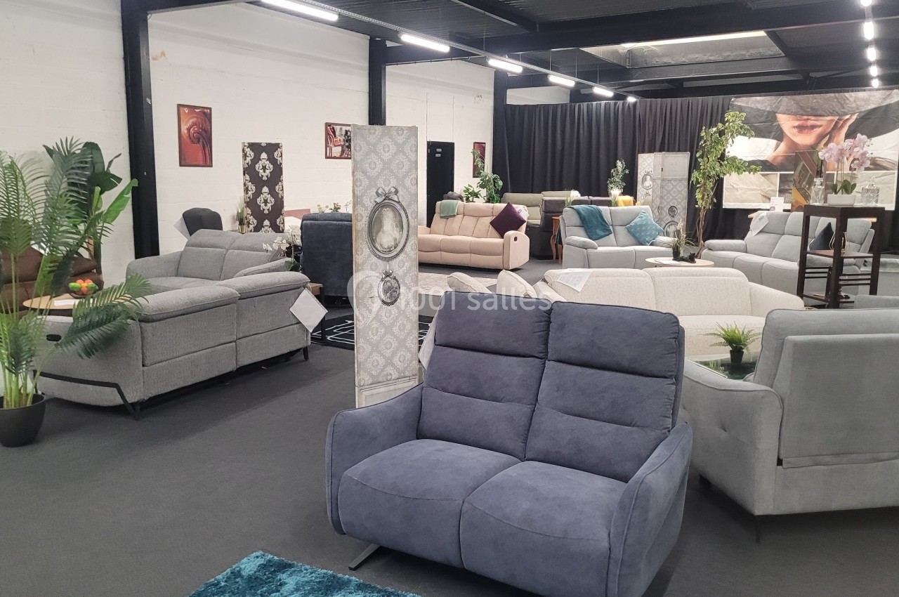 Salle d'exposition avec divers canapés modernes, plantes décoratives et séparateurs d'espace.