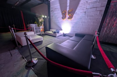 Miniature Location salle Seclin (Nord) - Luminaria #169 Décor festif avec ballons noirs, dorés, argentés et blancs, fond scintillant et deux tabourets blancs devant.