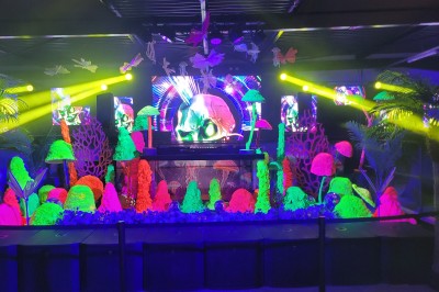 Deux mascottes en ours, blanc et rose, posent debout dans un espace intérieur animé avec des visiteurs.