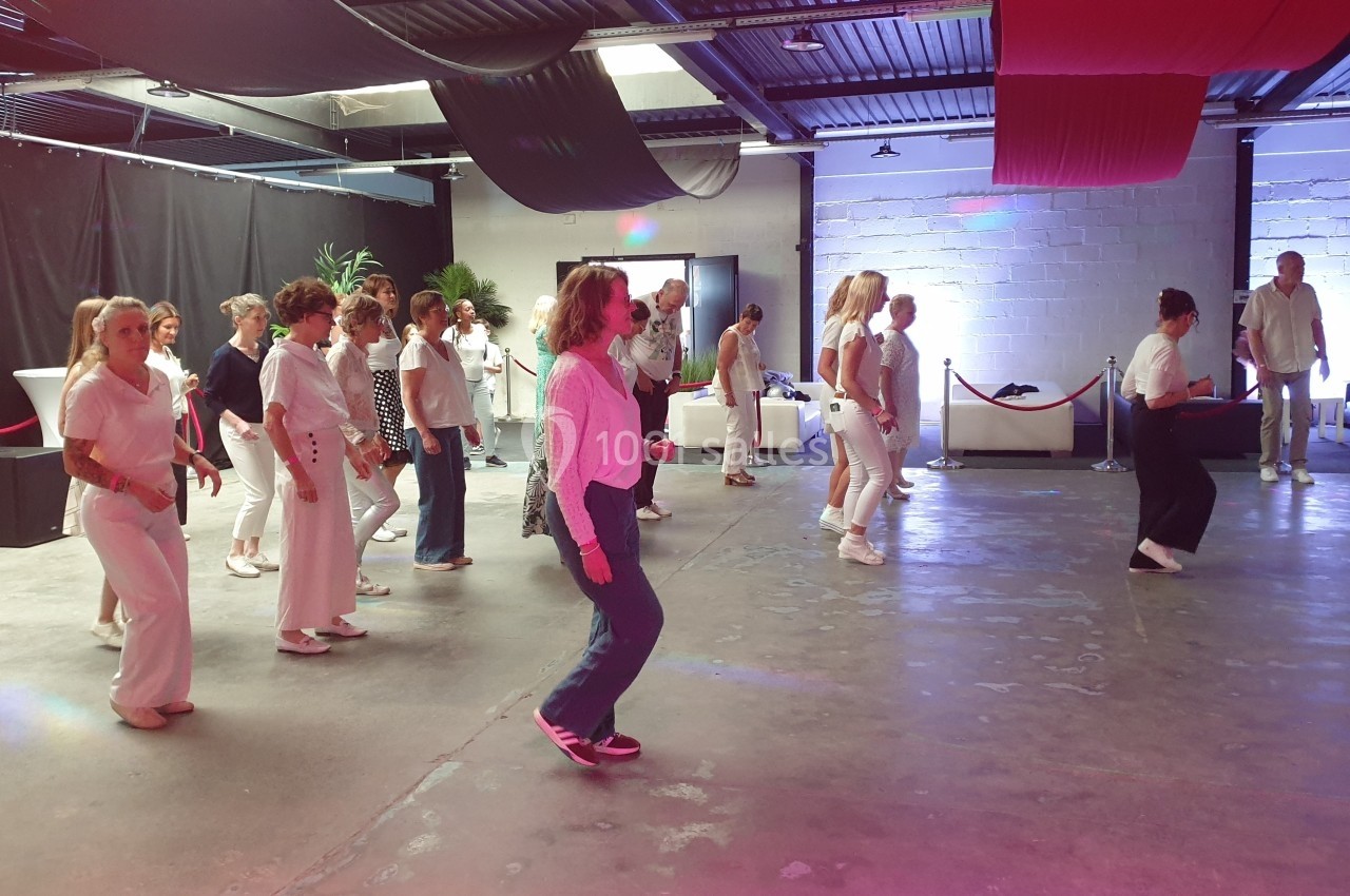 Groupe de personnes dansant en ligne dans une salle avec un éclairage coloré et un décor moderne.
