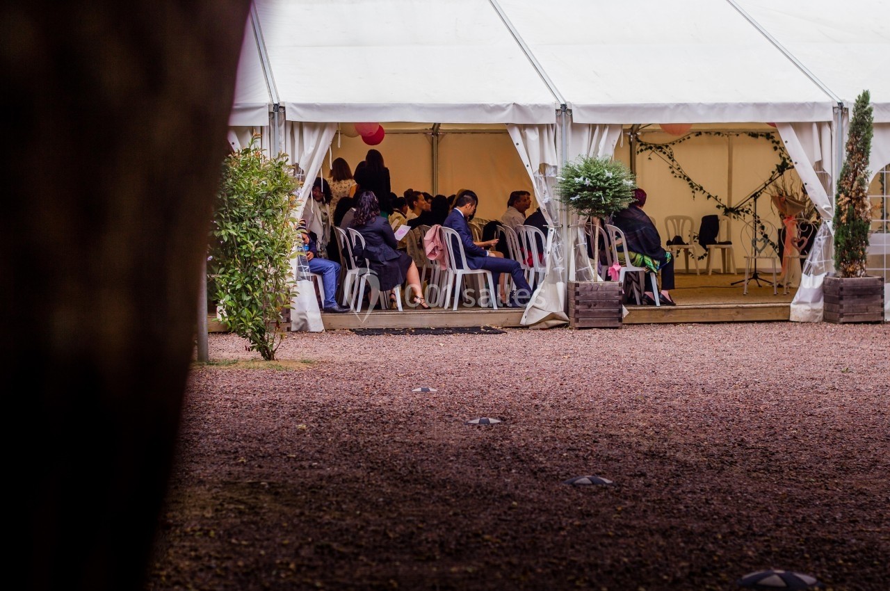 Location salle Reyrieux (Ain) - Le Clos Talançonnais #26 Des personnes assises sous une tente blanche ouverte, entourée de plantes, lors d'un événement en extérieur.