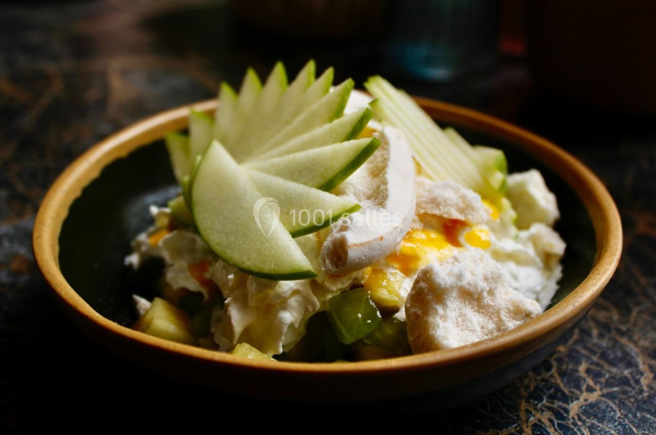 Bol contenant une salade de fruits garnie de tranches de pomme verte et de morceaux de meringue.