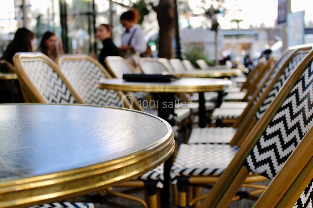 Chaises et tables en métal doré disposées en terrasse, avec des motifs en zigzag noir et blanc sur les assises.