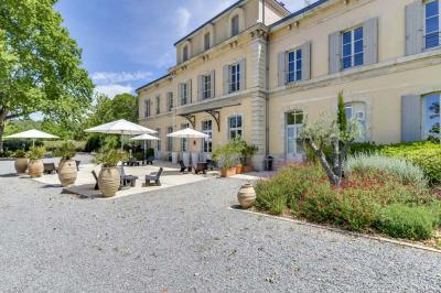 Miniature Location salle Sommières (Gard) - Domaine de l’Estelou #5 Grande table dressée en extérieur avec des chaises en bois, sous une pergola illuminée de lumières violettes, devant un…