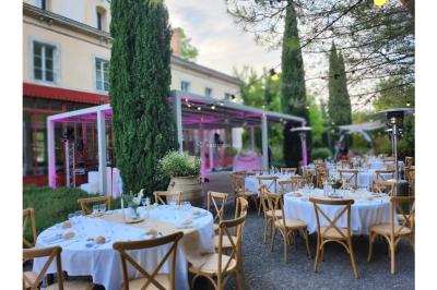 Miniature Location salle Sommières (Gard) - Domaine de l’Estelou #30 Grande table dressée en extérieur avec des chaises en bois, sous une pergola illuminée de lumières violettes, devant un…