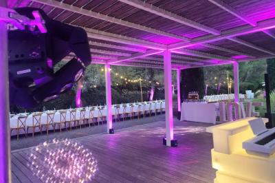 Miniature Location salle Sommières (Gard) - Domaine de l’Estelou #34 Grande table dressée en extérieur avec des chaises en bois, sous une pergola illuminée de lumières violettes, devant un…