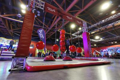 Parcours d'obstacles intérieur avec structures suspendues et ballons rouges, sous un éclairage de salle de loisirs.