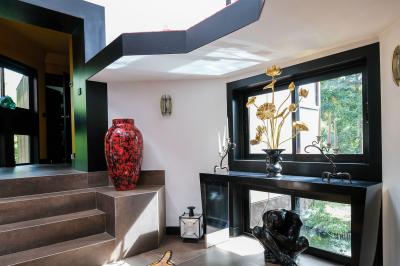 Maison contemporaine en cuivre avec grandes baies vitrées, terrasses et piscine, entourée de végétation.