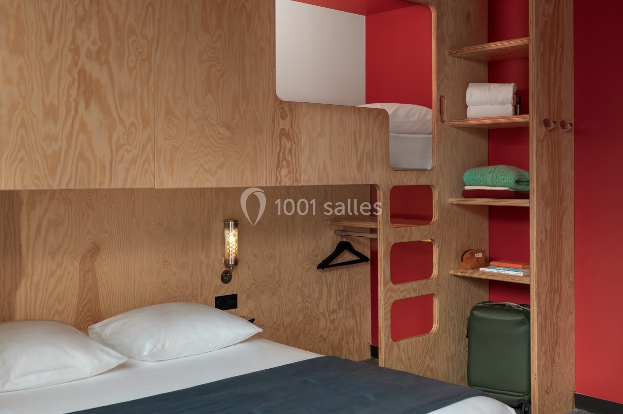 Lit double et lit superposé en bois dans une chambre moderne avec étagères, valise et décoration minimaliste.