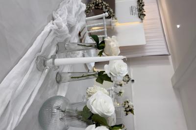 Miniature Leya Réception #13 Bougies blanches et roses dans des vases en verre décorent une table recouverte d'une nappe blanche.