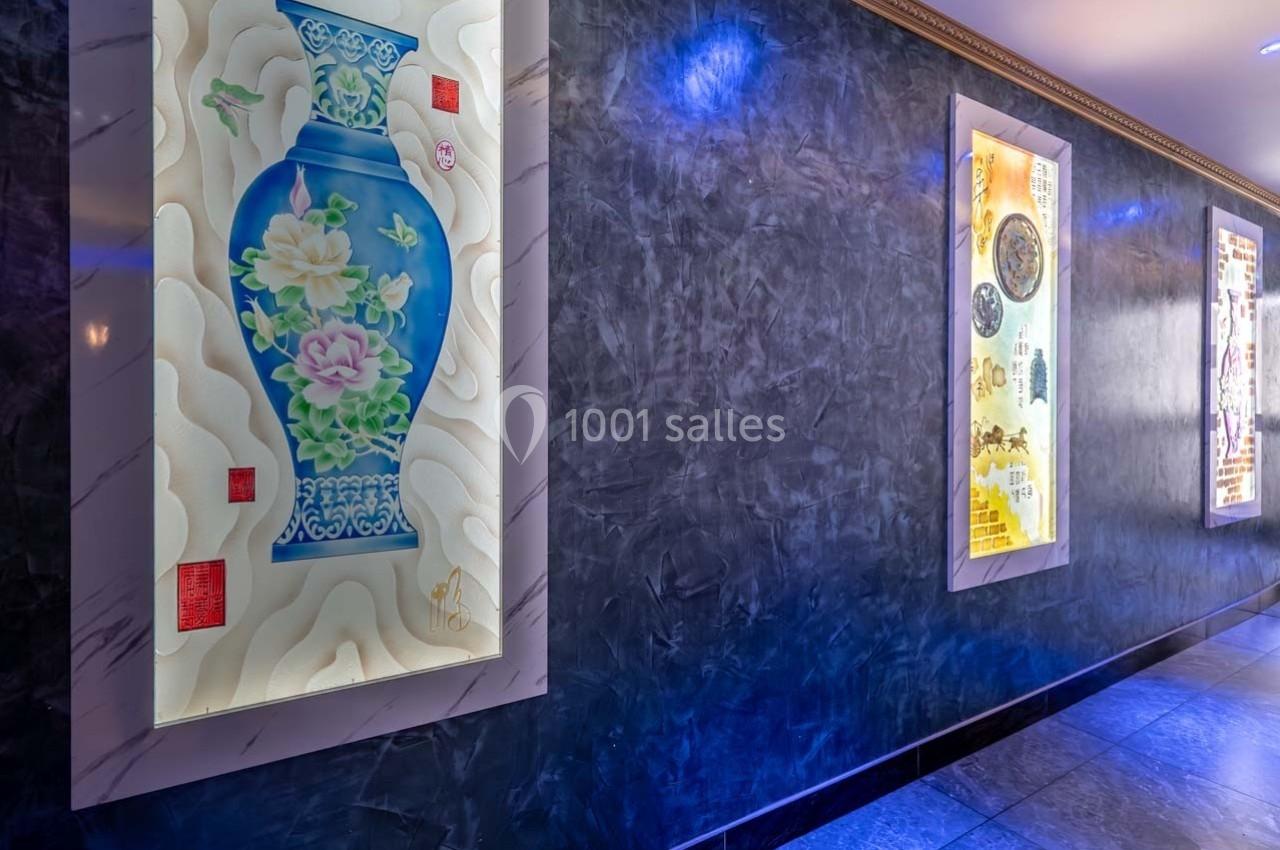 Tableaux lumineux représentant des motifs artistiques, accrochés sur un mur texturé dans un couloir éclairé.