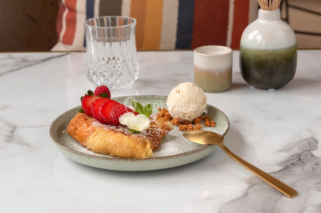 Assiette avec une pâtisserie garnie de fraises, crème glacée, miettes croustillantes et décorée de menthe.