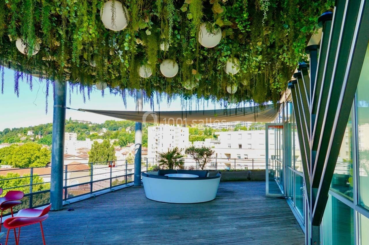 Location salle Caluire-et-Cuire (Rhône) - Le Belvédère #11 Terrasse avec plafond végétalisé, luminaires suspendus, mobilier moderne et vue sur des bâtiments urbains.