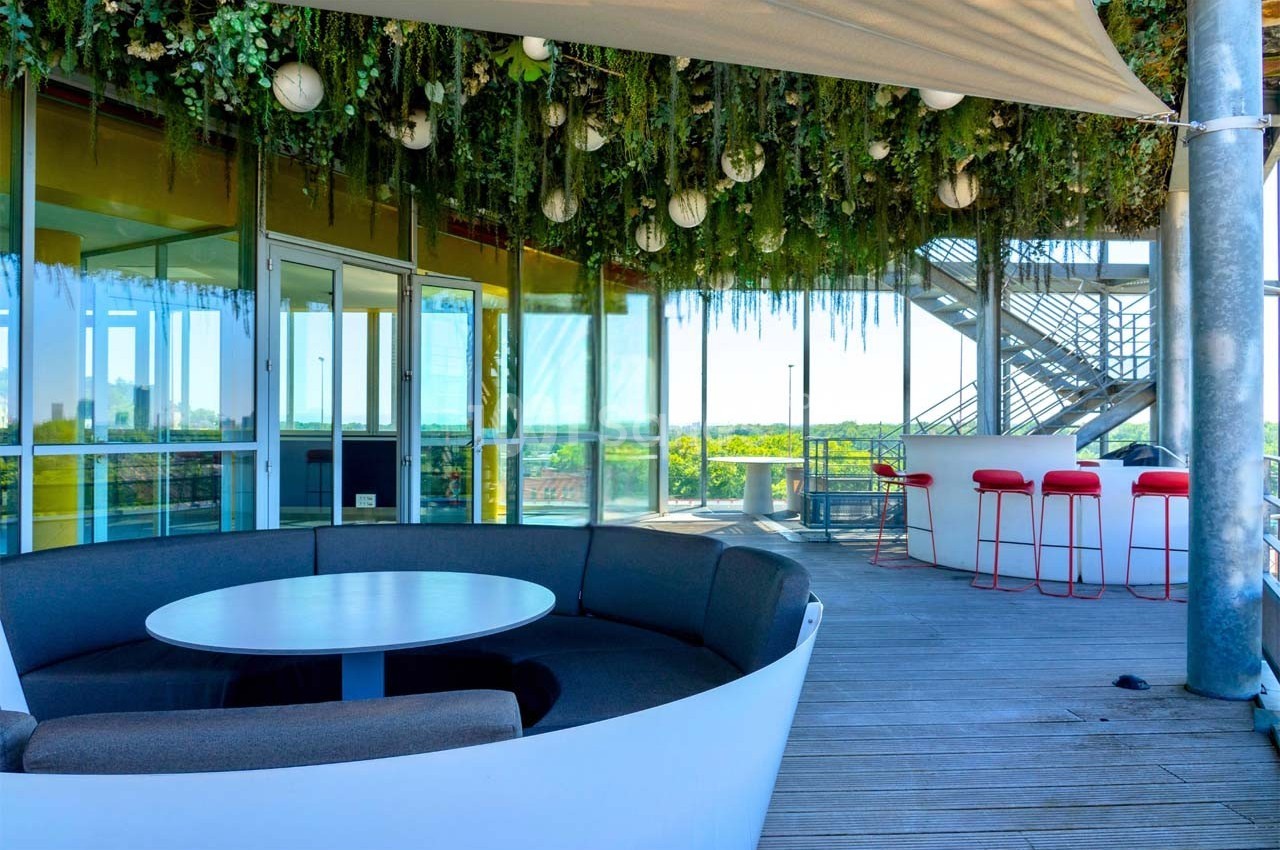 Espace extérieur avec mobilier moderne, plafond végétalisé et vue dégagée, aménagé sur une terrasse en bois.