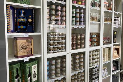 Étagères métalliques contenant diverses bouteilles d'alcool, alignées dans un entrepôt avec des cartons en dessous.