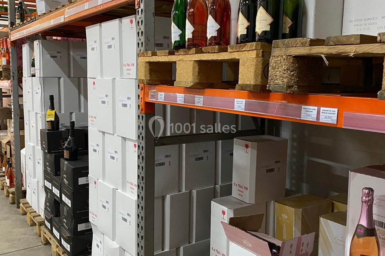 Rayonnages d'entrepôt avec des cartons de bouteilles de vin et de champagne empilés sur des palettes.