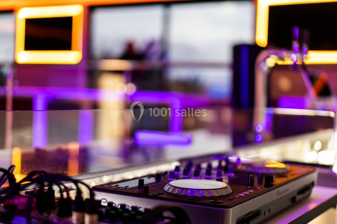Table de mixage avec éclairage néon violet et orange dans un espace moderne et lumineux.
