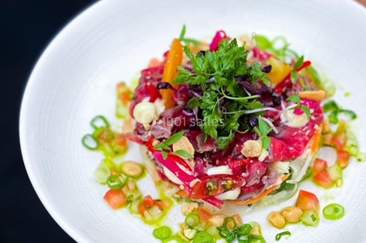 Assiette de tartare coloré avec légumes frais, herbes, oignons verts et garnitures croquantes, présentée sur une assiette…