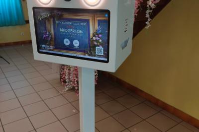 Miniature Anniversaire thème Bridgerton Des personnes dansent et discutent dans une salle éclairée par des lumières colorées lors d'un événement festif.