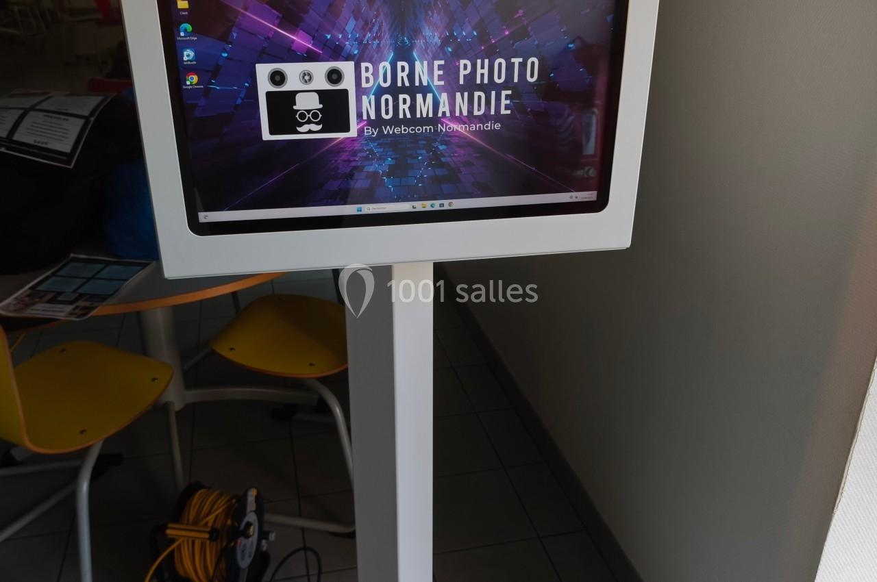 Borne photo interactive sur pied avec écran tactile et éclairage circulaire, installée dans un espace intérieur.