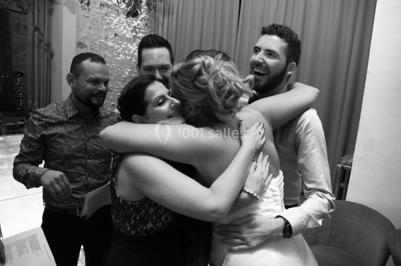 Un groupe de personnes souriantes se serre dans une étreinte chaleureuse lors d'un événement festif en intérieur.