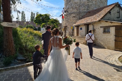 Chambre spacieuse sous combles avec poutres apparentes, lit double, coin salon coloré et grande baie vitrée.