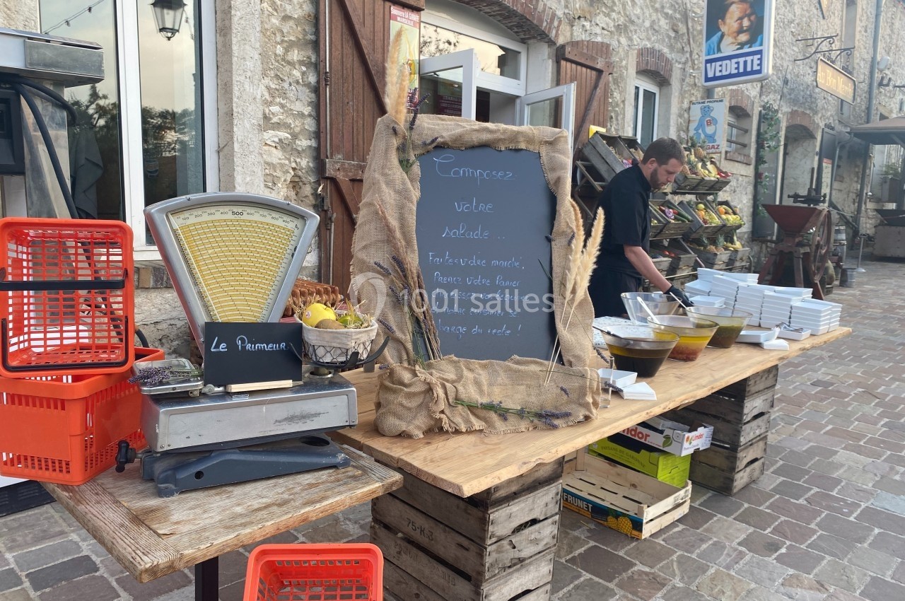 Stand en extérieur avec balance, ardoise proposant une salade à composer, bols d'ingrédients et caisses en bois.