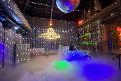 Chambre spacieuse sous combles avec poutres apparentes, lit double, coin salon coloré et grande baie vitrée.