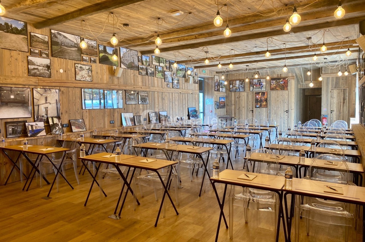 Salle de réunion en bois avec des tables, des chaises transparentes et des photos accrochées aux murs.
