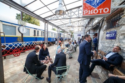 Un chef pâtissier en toque décore une tarte meringuée à l'extérieur, près d'un batteur sur socle.