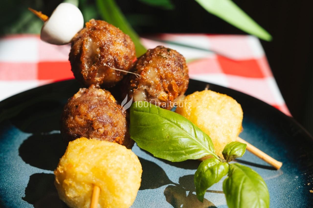 Brochettes avec boulettes de viande, fromage frit et feuille de basilic, servies sur une assiette bleue.
