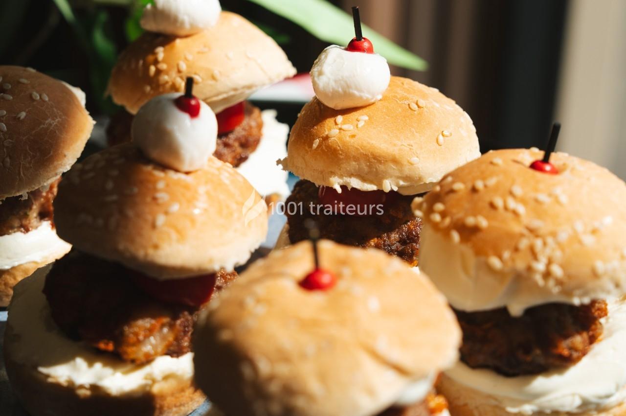 Mini burgers garnis de viande panée, fromage et décorés de boules de mozzarella et cerises sur des pics.