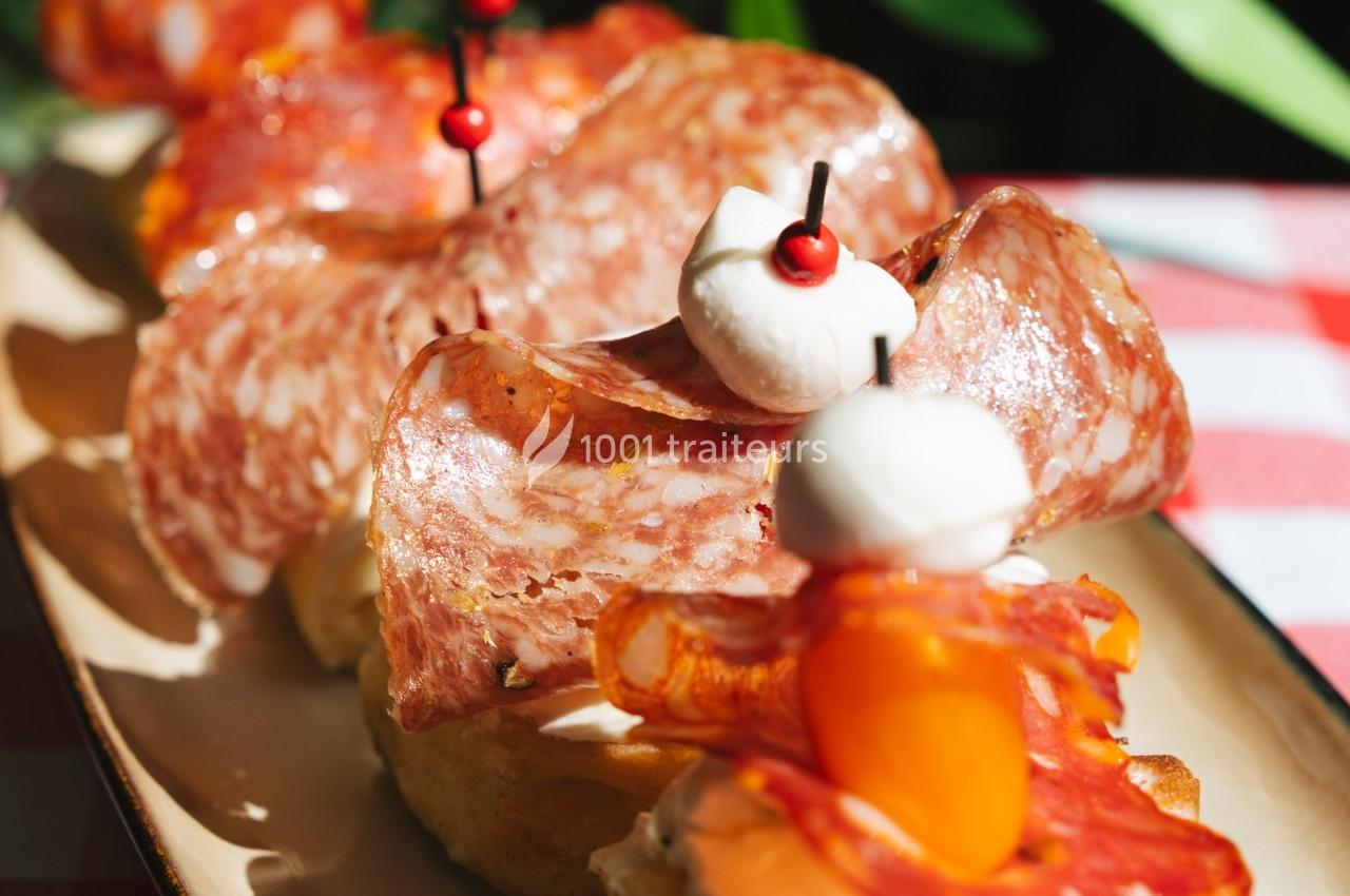 Tranches de charcuterie et mozzarella sur des toasts, décorés de tomates cerises et piques en bois.