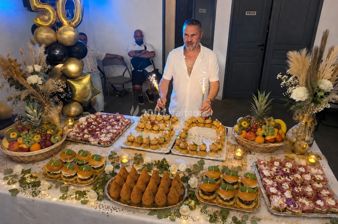 Un homme souriant derrière une table garnie de plats variés, décorée pour un 50e anniversaire.