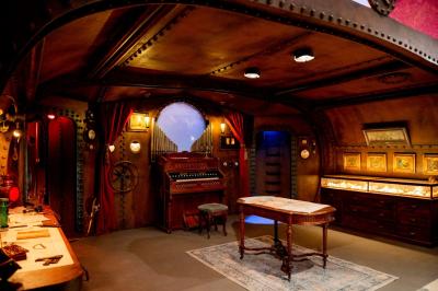 Vue d'un jardin verdoyant avec des arbres, des buissons et une grande cage métallique décorative au centre.