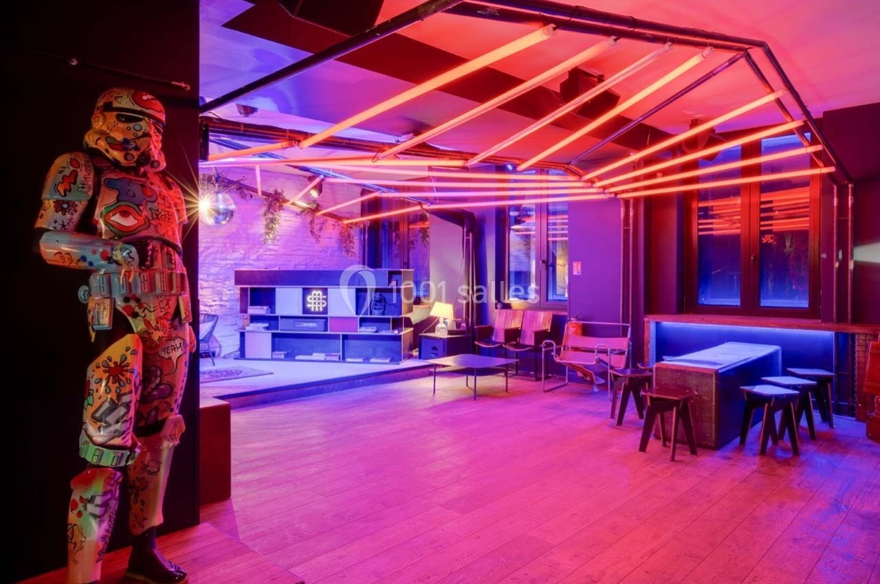 Salle moderne avec éclairage néon rouge, mobilier minimaliste et statue décorative colorée dans un coin.