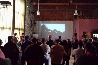 Chambre avec lit double bleu, tête de lit en rotin, décoration sobre et tableau représentant un ponton sur la mer.