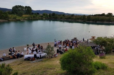 Chambre avec lit double bleu, tête de lit en rotin, décoration sobre et tableau représentant un ponton sur la mer.