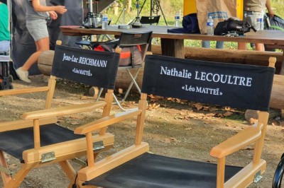 Chambre avec lit double bleu, tête de lit en rotin, décoration sobre et tableau représentant un ponton sur la mer.