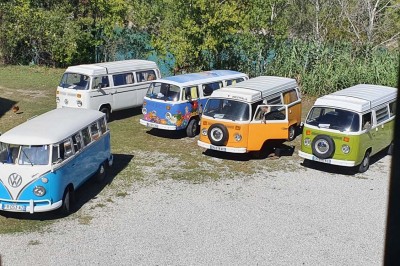Chambre avec lit double bleu, tête de lit en rotin, décoration sobre et tableau représentant un ponton sur la mer.