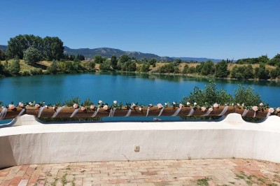 Chambre avec lit double bleu, tête de lit en rotin, décoration sobre et tableau représentant un ponton sur la mer.